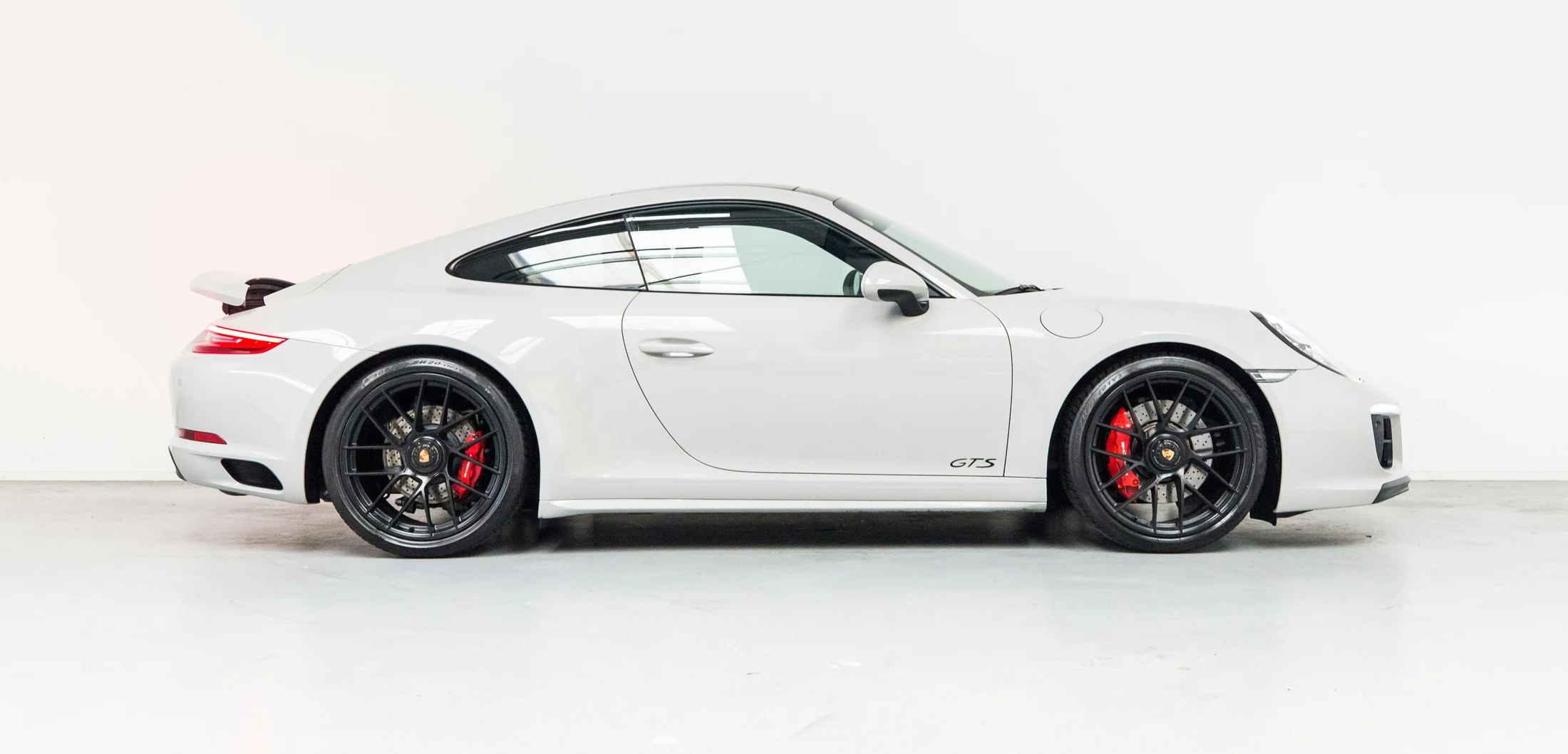 Porsche 911 Carrera 4 GTS branco, visto de perfil com pintura e rodas em destaque